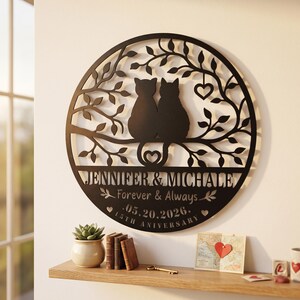 May include: A circular black metal wall sign featuring a silhouette of two cats sitting on a tree branch. The design includes the text JENNIFER & MICHALE, Forever & Always, 05.20.2026, and 15TH ANNIVERSARY, with decorative leaf and heart cutouts.