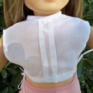 May include: A white, sleeveless blouse with a button-up front and a gathered waist. The blouse is made of a sheer fabric and has a simple, classic design.