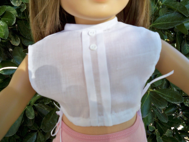 May include: A white, sleeveless blouse with a button-up front and a gathered waist. The blouse is made of a sheer fabric and has a simple, classic design.