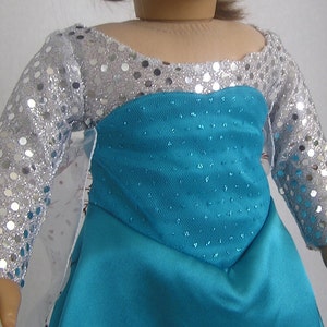 Puede incluir: Un vestido azul turquesa con mangas de lentejuelas plateadas. El vestido tiene un corpi&ntilde;o ajustado y una falda fluida.