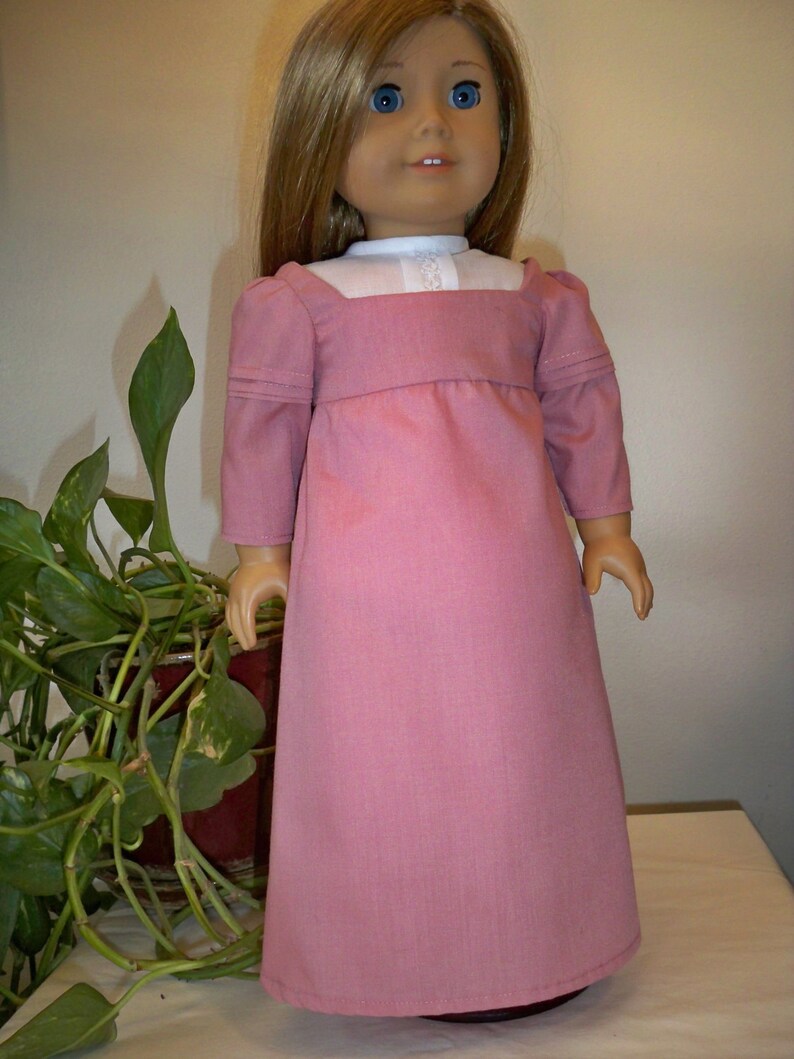May include: A pink dress with a white collar and long sleeves. The dress is made of a soft, textured fabric and has a simple, elegant design.