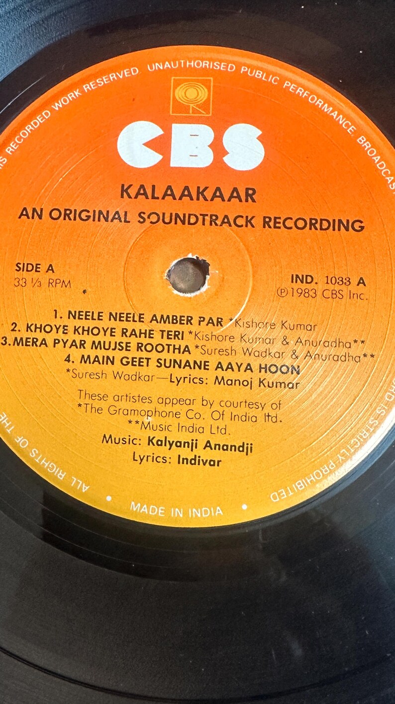 May include: A vintage vinyl record for the soundtrack "Kalaakaar" by CBS. The record label is orange with black text, listing song titles and credits. The record is a 33 1/3 RPM, made in India.