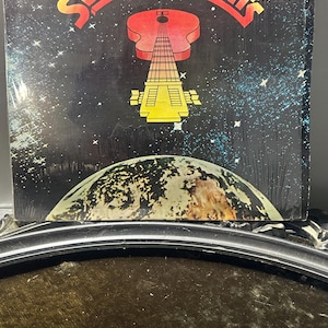 May include: Vintage vinyl record album cover for Sunil Ganguly's "Swinging Hits." The cover features a stylized guitar design in red and yellow against a starry night sky. The album title is in large, bold letters.