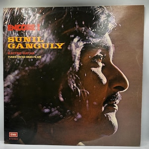 May include: Vintage vinyl record album cover featuring a profile of a man with a mustache. The album title is "Encore 1" by Sunil Ganguly, with the text "Electric Guitar Tunes From Hindi Films". The EMI Stereo logo is in the bottom left corner.