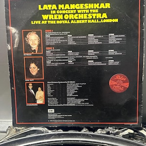 Könnte beinhalten: Vintage Vinyl-Schallplattenhülle mit "Lata Mangeshkar in Concert with the Wren Orchestra" live in der Royal Albert Hall, London. Das schwarze Cover hat weißen und gelben Text und enthält Fotos von Ed Welch und Sunil Dutt.