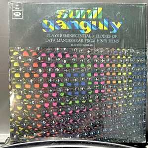 May include: A vinyl record album cover featuring the text "Sunil Ganguly" in a teal font. The album title reads "Plays Reminiscential Melodies of Lata Mangeshkar From Hindi Films." The background has a pattern of silver studs over a gradient of colors.