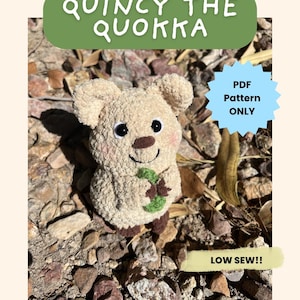 Puede incluir: Un peluche de quokka beige con una nariz marrón y ojos negros. El quokka sostiene una ramita verde y tiene mejillas rosadas. El texto en la imagen dice "Quincy the Quokka", "PDF Pattern ONLY" y "LOW SEW!!".