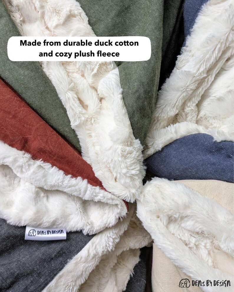 May include: Close-up of a patchwork blanket with various fabric textures and colors. The blanket features a plush white fleece border and is made from durable duck cotton. The text "Made from durable duck cotton and cozy plush fleece" is visible.