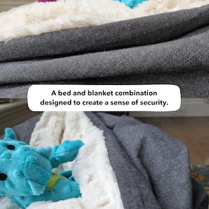 May include: A bed and blanket combination designed to create a sense of security. The image shows a gray bed with a white fluffy blanket and a blue stuffed animal. The text in the image says "A bed and blanket combination designed to create a sense of security."