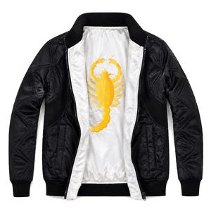 Può includere: Un giubbotto bomber nero trapuntato con fodera interna bianca. Il retro del giubbotto presenta un grande disegno ricamato di uno scorpione giallo. Il capo è dotato di colletto, polsini e orlo a coste neri e chiusura frontale con cerniera.