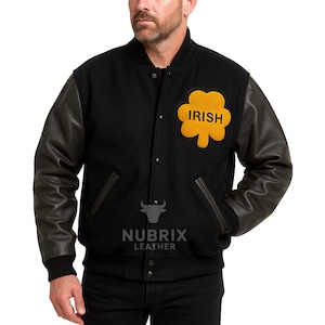 Könnte beinhalten: Schwarze Collegejacke mit Lederärmeln. Die Jacke hat einen gelben Kleeblatt-Aufnäher mit dem Wort "IRISH" in schwarzen Buchstaben. Die Jacke hat eine Knopfleiste und zwei Vordertaschen.