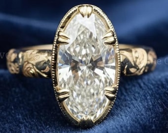 May include: A gold ring with an oval-shaped, clear gemstone. The ring has an ornate, floral design on the band and around the gemstone. The ring is set against a dark blue background. The text "Motivone Craft" is visible.