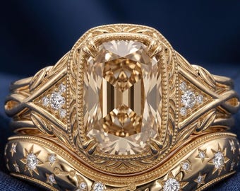 May include: A gold ring set featuring a large, rectangular, champagne-colored center stone surrounded by intricate filigree metalwork. The band includes a curved, celestial-themed wedding band adorned with small, embedded white stones in star and moon shapes.