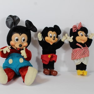 May include: Three vintage Mickey Mouse and Minnie Mouse plush dolls. Mickey is in red and blue, Minnie in a red polka dot dress. All have black ears and smiling faces.