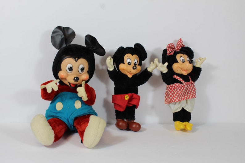 May include: Three vintage Mickey Mouse and Minnie Mouse plush dolls. Mickey is in red and blue, Minnie in a red polka dot dress. All have black ears and smiling faces.
