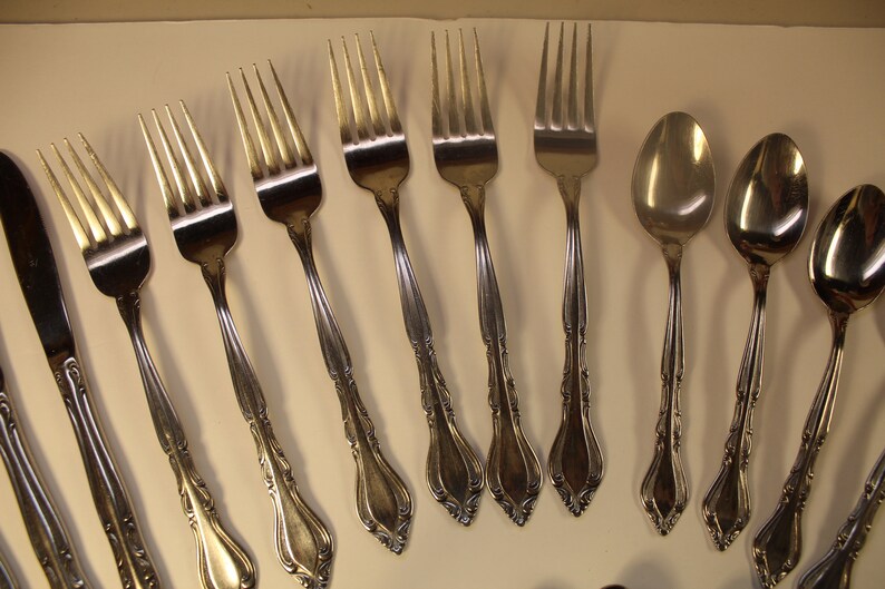 May include: A set of silverware with a decorative design. The set includes forks, spoons, and a butter knife.
