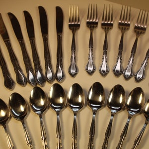 May include: A set of silverware with a decorative design. The set includes spoons, forks, and knives.