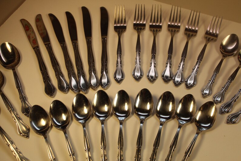 May include: A set of silverware with a decorative design. The set includes spoons, forks, and knives.