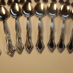 May include: A set of silver spoons with ornate handles. The spoons are arranged in a row, with the handles pointing towards the right.