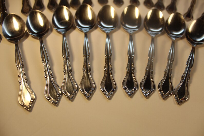 May include: A set of silver spoons with ornate handles. The spoons are arranged in a row, with the handles pointing towards the right.