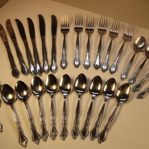May include: A set of silverware with a decorative design. The set includes forks, spoons, and knives.