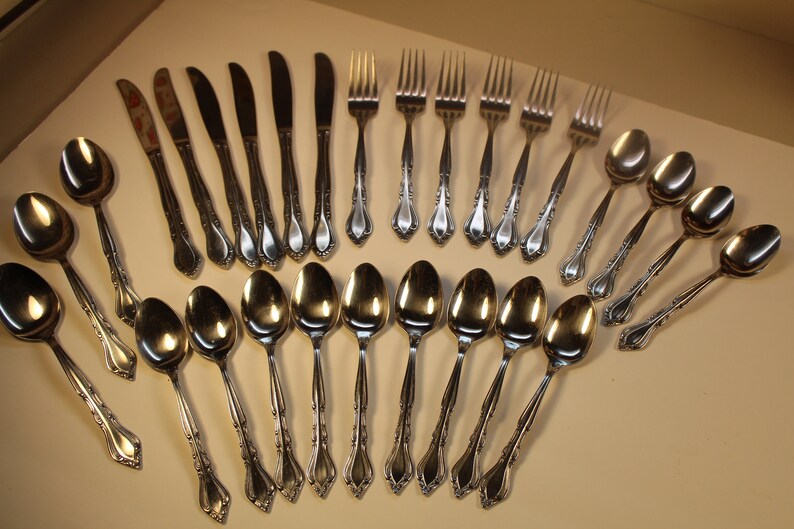 May include: A set of silverware with a decorative design. The set includes forks, spoons, and knives.