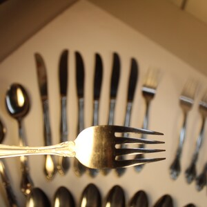 May include: A set of silver flatware, including forks, knives, and spoons. The flatware has an ornate design with a floral pattern.