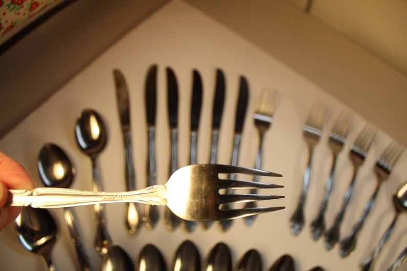 May include: A set of silver flatware, including forks, knives, and spoons. The flatware has an ornate design with a floral pattern.