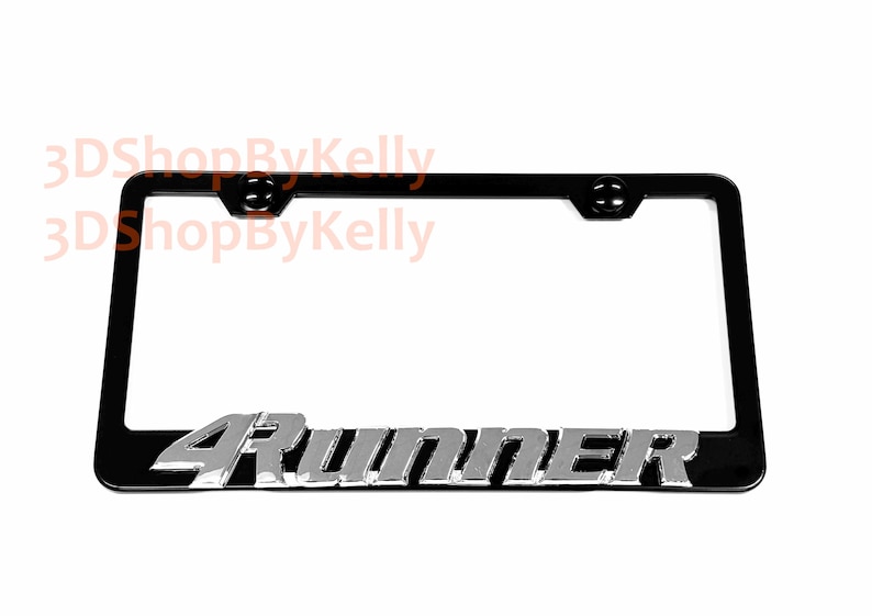 May include: A black license plate frame featuring the silver-colored text 4Runner embossed along the bottom edge. The frame includes two mounting holes at the top and displays the watermark text 3DShopByKelly in the upper left corner.