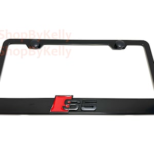 May include: Black license plate frame with the letters "S5" in red and black. The frame has a rectangular shape with rounded corners and two black screw caps at the top.