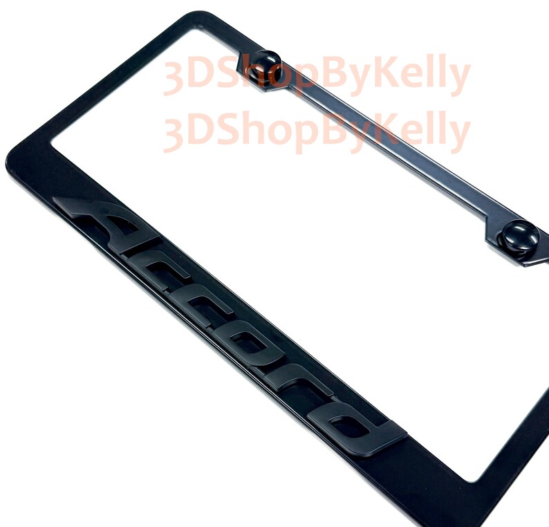 May include: A black license plate frame featuring the word ACCORD in raised, bold, black lettering along the bottom edge. The frame includes two black circular screw covers at the top and displays the text 3DShopByKelly in light orange.
