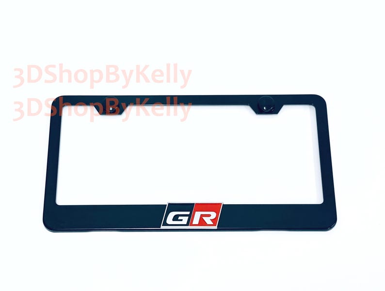 May include: A black rectangular license plate frame featuring the letters GR in white, set against a red and black background block at the bottom center. The frame includes two mounting holes at the top and the text 3DShopByKelly in light red.