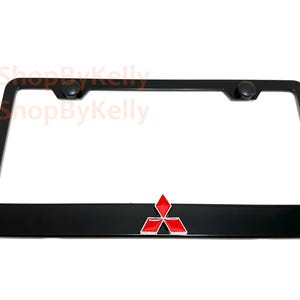 May include: Black license plate frame with a red and silver Mitsubishi logo. The frame has a glossy finish and includes two black screw caps at the top. The Mitsubishi logo is a three-diamond design.