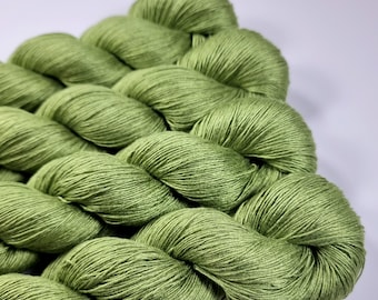 May include: Close-up of a skein of green yarn. The yarn is a light, spring green color and appears soft and textured. The yarn is arranged in a twisted, rope-like pattern, suggesting it is ready for knitting or crocheting projects.