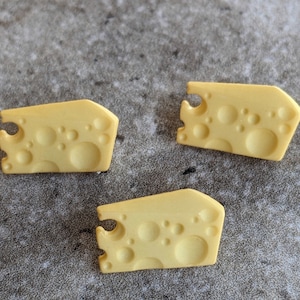 May include: Three yellow plastic cheese-shaped buttons with holes.