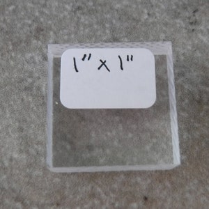 May include: A clear acrylic sheet measuring 1 inch by 1 inch.