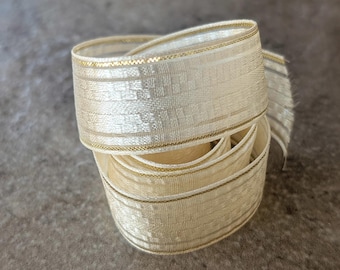 May include: A roll of ivory-colored ribbon with gold trim. The ribbon has a subtle striped pattern and a delicate, shimmering texture. The edges are finished with a thin gold thread. Perfect for crafts and gift wrapping.
