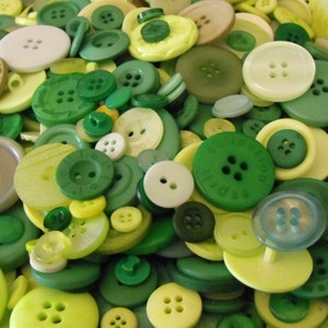 May include: A collection of green, yellow, and white buttons in various sizes and patterns. The buttons are made of plastic and have a smooth finish.