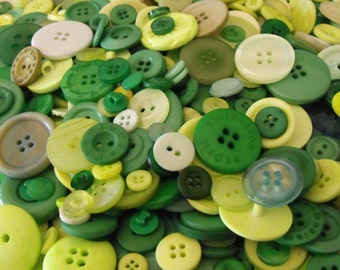 May include: A collection of green, yellow, and white buttons in various sizes and patterns. The buttons are made of plastic and have a smooth finish.