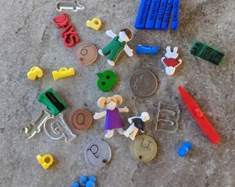 May include: A collection of colorful plastic and wooden toys, including a green apple, a purple girl doll, a red heart, a blue boy doll, a green and yellow pencil, a red and white striped pencil, a blue and white coin, and a variety of letters and numbers.