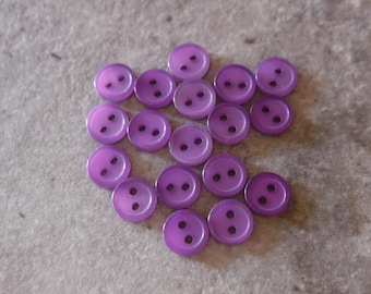 May include: A collection of 18 purple plastic buttons with two holes each.