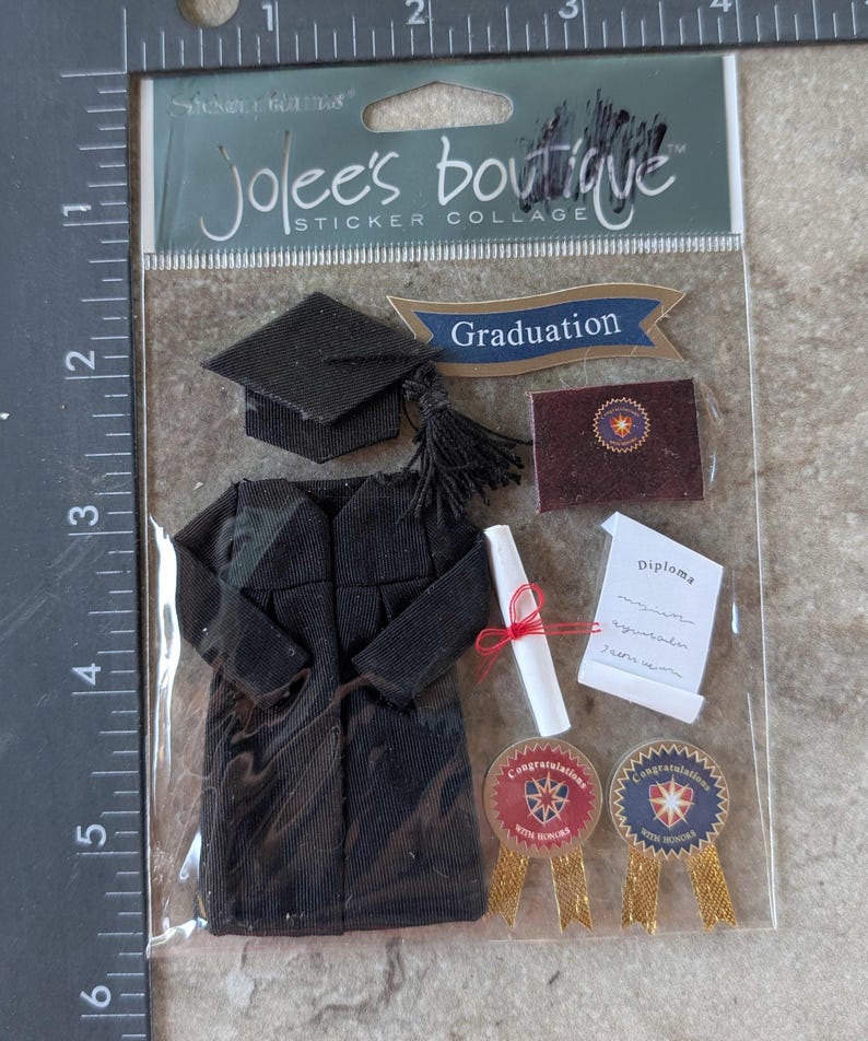 May include: A sticker collage by Jolee's Boutique featuring graduation-themed embellishments. Includes a black graduation cap, gown, diploma, and ribbons with the text "Congratulations With Honors". A banner reads "Graduation".