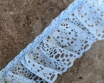 May include: Light blue lace trim with a delicate floral pattern. The lace is ruffled and has a sheer texture.