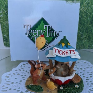 May include: A Teeny Tiny figurine set featuring a squirrel holding a yellow balloon and a mouse at a red and blue ticket booth. The figurine is made of painted resin and is approximately 3 inches tall.