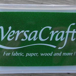May include: A green ink pad with the text "VersaCraft&trade;" in white lettering. The text "For fabric, paper, wood and more!" is also printed in white on the pad.