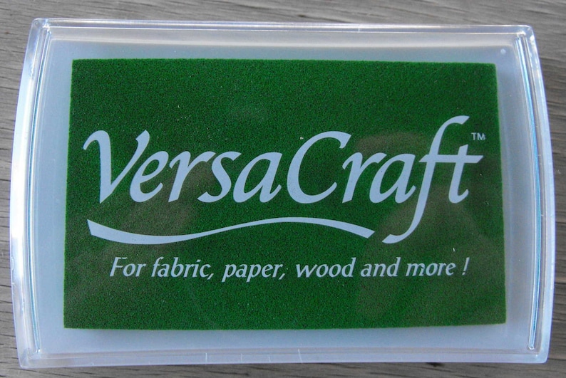 May include: A green ink pad with the text "VersaCraft&trade;" in white lettering. The text "For fabric, paper, wood and more!" is also printed in white on the pad.
