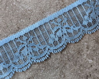 May include: Light blue lace trim with a scalloped edge. The lace has a delicate floral pattern.