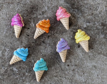 May include: Assortment of seven glittery ice cream cone shaped ornaments in various colors, including pink, purple, blue, yellow, and orange.