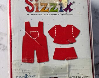 May include: Red die-cut doll overalls and shirt set for crafting. The package includes the Sizzix logo and the text "The Little Die-Cutter That Makes a Big Difference." The package also includes the text "Brought to you by: PROVO CRAFT Ellison" and "38-0104 Doll Overalls Actual Size on Back".