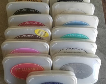 May include: A stack of 12 archival pigment ink pads in various colors, including black, brown, red, blue, green, pink, and silver. The ink pads are labeled "Archival" and "Brilliance".